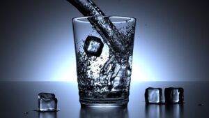 Wasser wird in ein Glas mit Eiswürfeln eingeschüttet