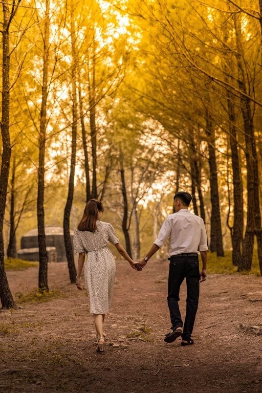 Paar geht Hand in Hand durch einen herbstlichen Wald